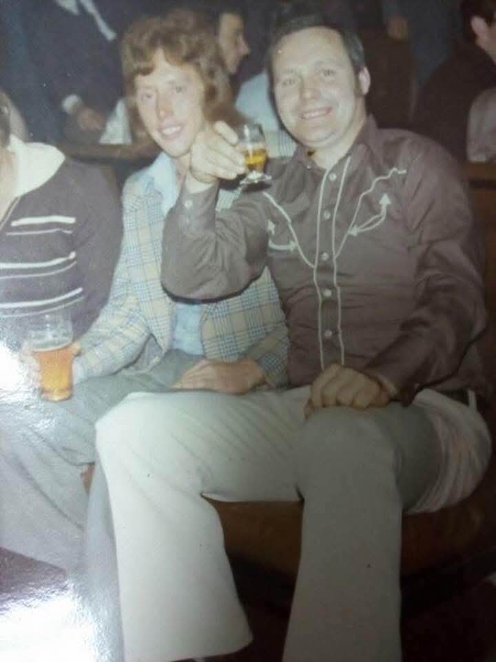 A family photograph of a smiling couple seated at a table